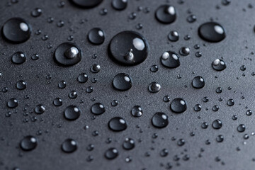 black plastic covered with water drops, details of the wet part of an object made of black plastic