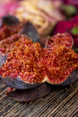 moldy whole overripe and spoiled figs with red flesh and seeds on a table, moldy spoiled figs with lots of grains