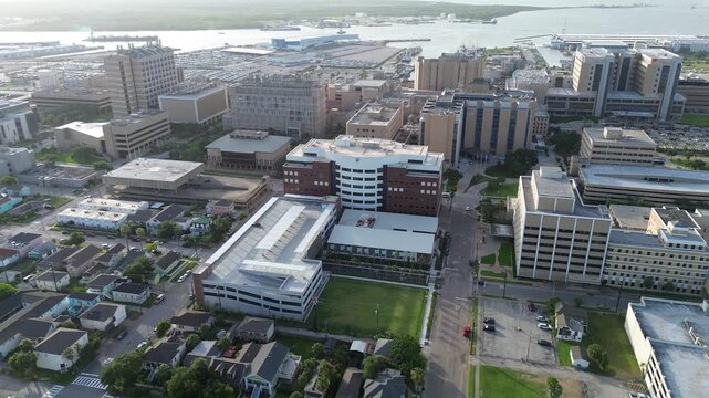 City blocks featuring older, large-format commercial and institutional buildings at the heart of Galveston downtown, high-rise office campus near historic residential houses, port activities