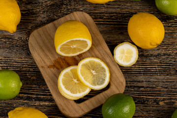sliced juicy yellow sour lemon lying on the table with green limes, sliced ripe citrus fruits lemon and limes on a wooden table