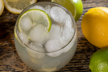 cold lemon drink with the addition of pieces of pure ice in a glass, sweet and sour refreshing drink with lemon flavor and juicy lemons and limes