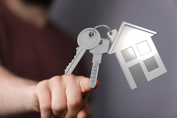 Close up of person hand holding keys with a house shaped key chain. Property investment, new home...