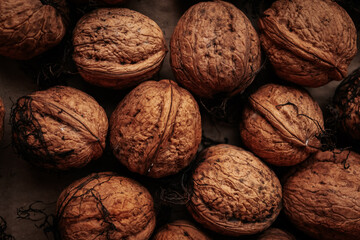 A rustic arrangement of whole walnuts scattered on a brown paper surface reveals natural textures and earthy tones. Soft lighting creates a warm, organic feel.