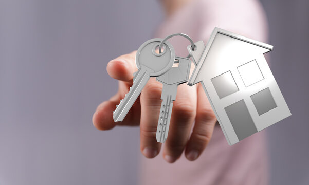 A hand presents house keys attached to a house-shaped keychain, representing home ownership, new beginnings, and the realization of a dream. Per - Powered by Adobe