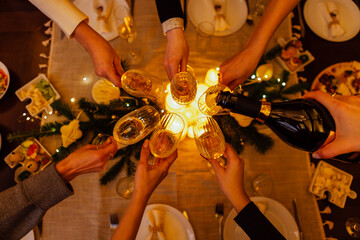 Group of diverse hands toasting with champagne glasses around a festive table adorned with food and decorations, celebrating a joyful occasion with warmth and togetherness