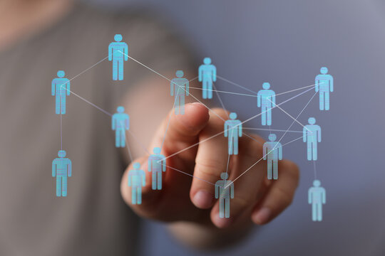 Hand touching digital network of people, representing connections and teamwork, and global communication.