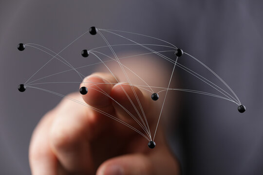 Hand reaching toward a digital network of interconnected nodes, representing concepts like connection, technolo