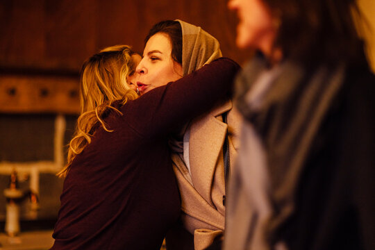 A young woman hugs her friend at home. The girl greets the guest with friendly hugs in the house.