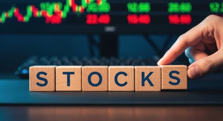 Wooden blocks spelling STOCKS a concept for stock market investment and trading with stock ticker in the background