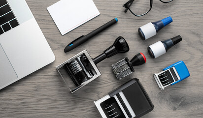Office desk with stamps, ink bottles, laptop, and stationery top view