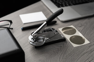 Embossing tool with foil sticker and office items on wooden table