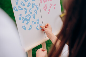 Hand placing sticker on gender reveal voting board