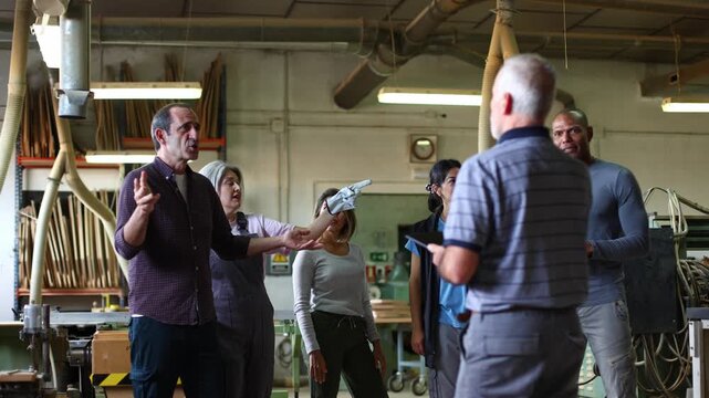Mature carpenter teaching woodworking class in workshop