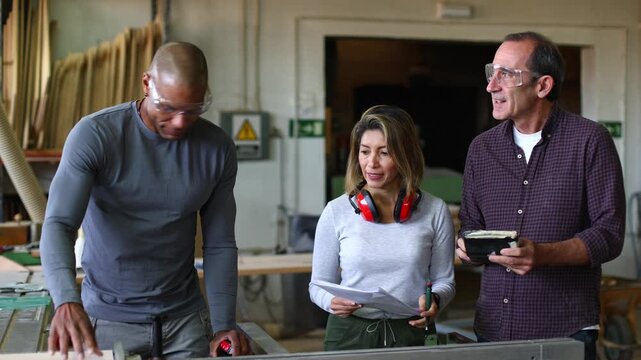 Carpenter measuring wood plank during team meeting