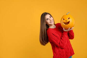 Happy Halloween. Woman with carved Jack-o'-lantern pumpkin on yellow background. Space for text