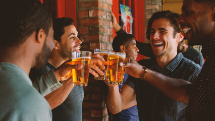 Group Of Male Friends Meeting In Sports Bar Making Toast Together