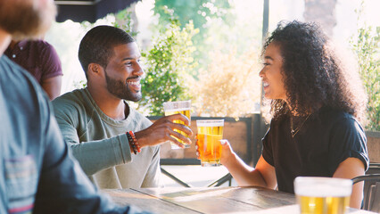 Young Couple Meeting In Sports Bar Enjoying Drink Before Game