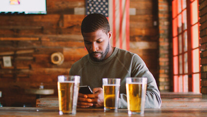 Man In Sports Bar Waiting For Friends Using Mobile Phone