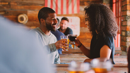 Young Couple Meeting In Sports Bar Enjoying Drink Before Game