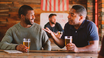 Two Male Friends Meeting In Sports Bar Enjoying Drink Before Game