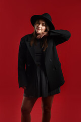 Fototapeta premium Beautiful young woman in stylish clothes posing on red background
