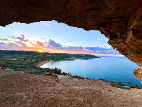 Golden sunset over ramla bay from tal-mixta cave in gozo, malta