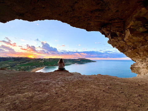Tourist watching ramla bay sunset from calypso cave in gozo, malta
