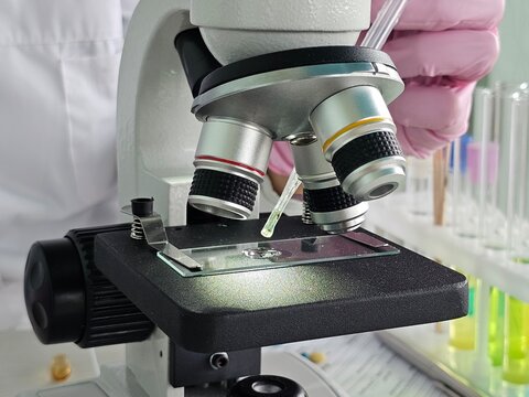 Scientist using a microscope to observe a specimen in a laboratory setting during a research session concept