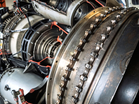 Close-up view of an aircraft engine section showing metal bolts, rings, and turbine components, highlighting the engineering precision, mechanical complexity, and industrial craftsmanship.