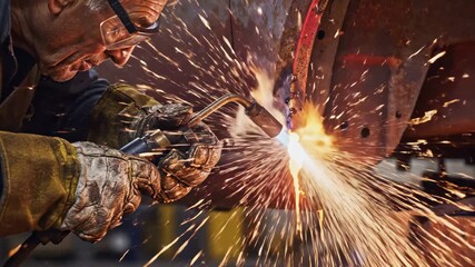 Auto mechanic welding rusted car body with a torch, showering bright sparks as he repairs and restores metal panels in a gritty workshop, focused on precision and safety