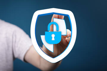 Hand holding a shield graphic with a padlock symbolizing digital security, protection and safety of...