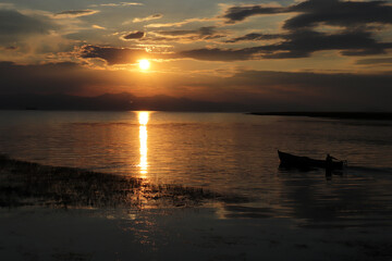 A fisherman with his boat at sunset