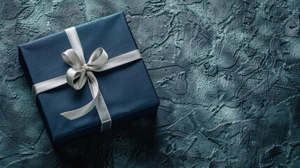 Luxury dark blue gift box tied with a shiny silver ribbon, placed on textured dark background for a classy celebration theme.