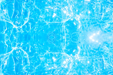 Blue water with ripples on the surface. Defocus blurred transparent blue colored clear calm water surface texture with splashes and bubbles. Water waves with shining pattern texture background.