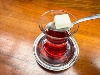 Traditional Turkish tea served in a classic curved glass with a sugar cube on a spoon symbolizing authentic national beverage culture