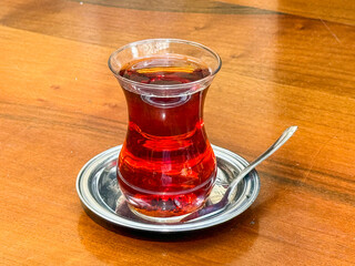 Traditional Turkish tea in a glass cup served on a wooden table highlighting national culture and authentic beverage ritual