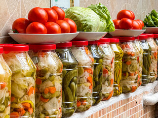 Row of traditional Turkish pickled vegetables in jars with tomatoes and lettuce placed above reflecting authentic homemade cuisine