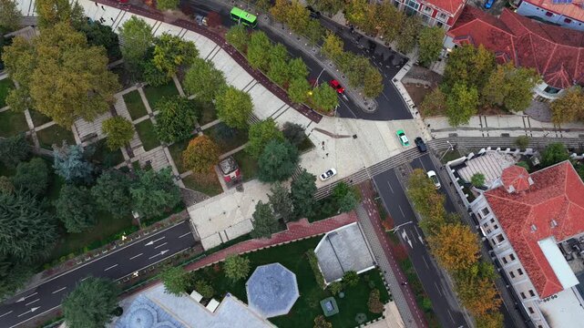 Aerial top-down video of Tirana, Albania, Elbasani road, autumn trees, and surrounding urban architecture.