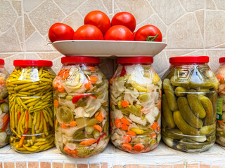 Assorted homemade pickled vegetables in glass jars with fresh tomatoes arranged above representing traditional Turkish food culture