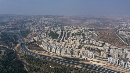 Obraz premium Aerial view of Highway 1 and Ramat Shlomo JerusalemA sweeping view of Ramat Shlomo’s dense residential blocks rising above the main Jerusalem–Tel Aviv highway.