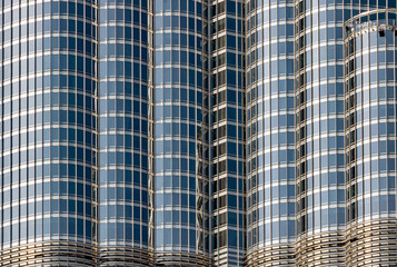 A close-up view of sleek glass building featuring curved, reflective facades and grid-like windows.