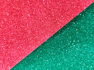 Diagonal split background of red and green glitter paper creating a festive sparkling texture. Shiny abstract surface ideal for holiday, celebration, and decorative design concepts.
