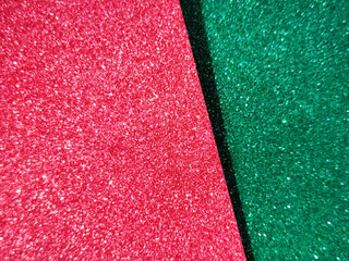 Diagonal split background of red and green glitter paper creating a festive sparkling texture. Shiny abstract surface ideal for holiday, celebration, and decorative design concepts.