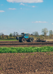 Obraz premium The tractor plows the soil in the field. Selective focus.