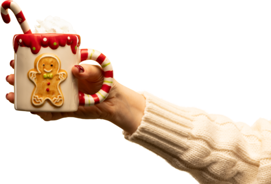 Hand holding gingerbread-themed holiday mug with candy cane and cream on transparent background. Concept of Christmas marketing, cozy lifestyle visuals, festive sweets, and warm emotional storytelling
