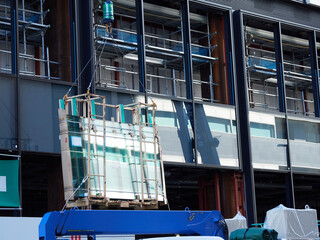 都市の建設中の高層ビルの仕組みとガラスを運搬する様子