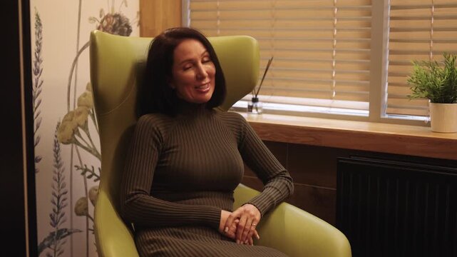 Woman client having confidential one-on-one session with professional psychotherapist, discussing mental health concerns and receiving counseling in dark private office setting.