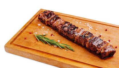 Grilled pork kebab with herbs resting on a wooden cutting board