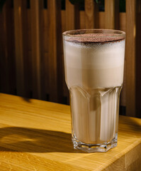 Delicious creamy drink served in a tall glass on a wooden table