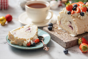 Homemade Meringue Cake Sweets Roll with strawberries and blueberries jam on granite board.